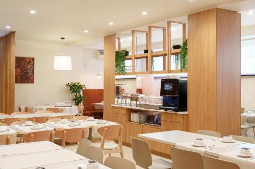 a restaurant with white tables and chairs and a tv at Hotel Santo António de Pádua in Fátima
