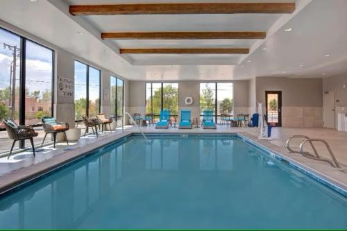 a pool in a hotel with blue chairs and windows at Hampton Inn Santa Fe South, NM in Santa Fe