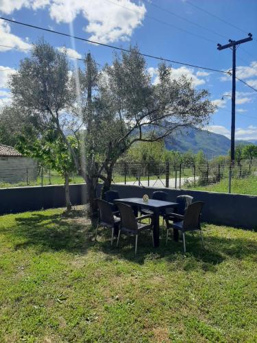 a table and chairs in a yard with a tree at Meteora view Guesthouse in Kalabaka