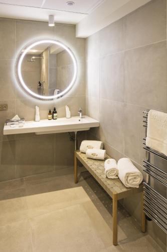 a bathroom with a sink and a mirror and towels at Hôtel & Spa Villa Seren in Hossegor