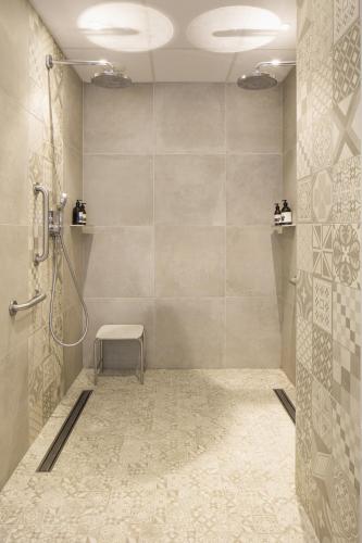 a bathroom with a shower with a bench in it at Hôtel & Spa Villa Seren in Hossegor