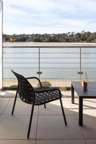 a chair and table on a balcony with a view of the ocean at Hôtel & Spa Villa Seren in Hossegor