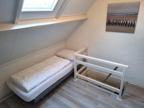 a small bed in a room with a window at Vakantiewoning met terras vlakbij strand en centrum in Zoutelande