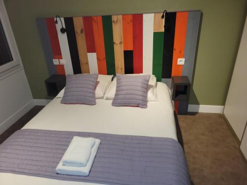 a bedroom with a bed with purple sheets and pillows at Hôtel Les Rives D'Allier in Mazeyrat-d'Allier