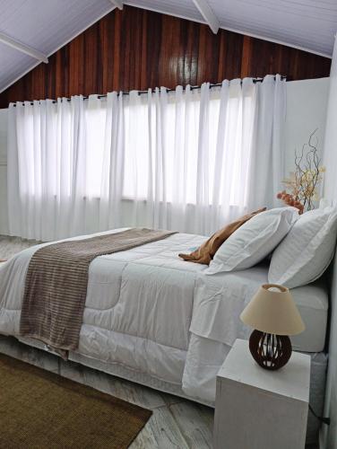 a bedroom with a white bed with a wooden wall at Chalé do Mato in Itatiaia
