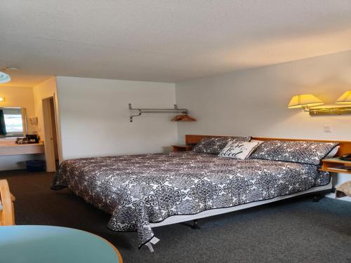 a bedroom with a bed and a table with a lamp at Ponderosa Motor Inn in Golden
