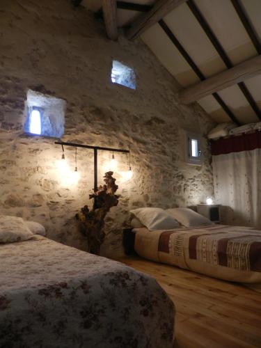une chambre avec deux lits et un mur en pierre dans l'établissement Véritable mas provençal avec 3 logements en pleine nature, à Cavillargues