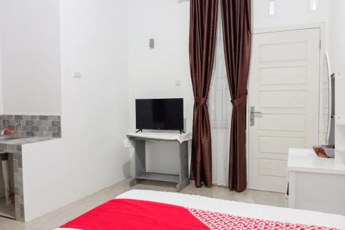 a bedroom with a bed and a tv and a door at Hotel O Homestay Jaya Putri 1 Syariah in Bandar Lampung