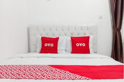 a white bed with two red pillows on it at Hotel O Homestay Jaya Putri 1 Syariah in Bandar Lampung
