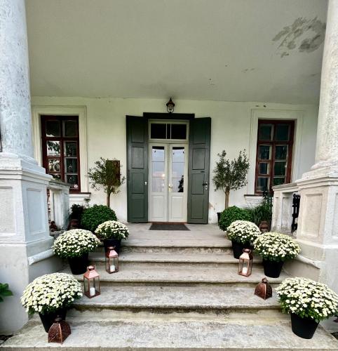 a front door of a house with stairs and flowers at Blankenfeldes muiža in Tērvete