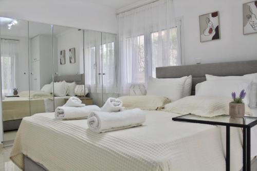 a white bedroom with two towels on a bed at Bright and Peaceful Apartment near Varkiza beach in Varkiza