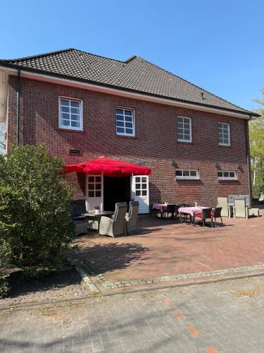 HarkebrüggeにあるGasthaus Blockのテーブルと椅子と赤い傘のあるレンガ造りの建物