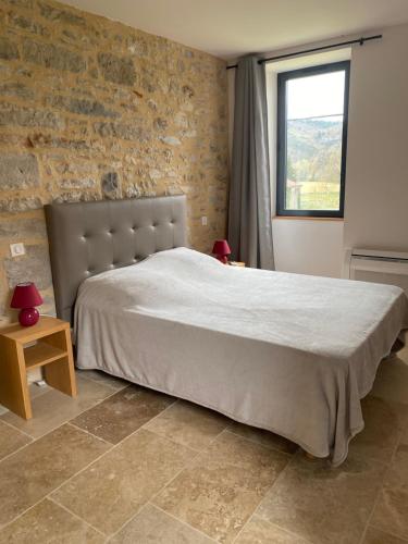a bedroom with a large bed and a brick wall at Gite le Roucayral , vue imprenable sur St Cirq Lapopie, deux chambres climatisées in Tour-de-Faure