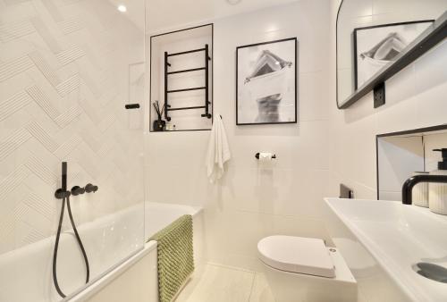 a white bathroom with a toilet and a sink at Newly Refurbished w/ River Views in London