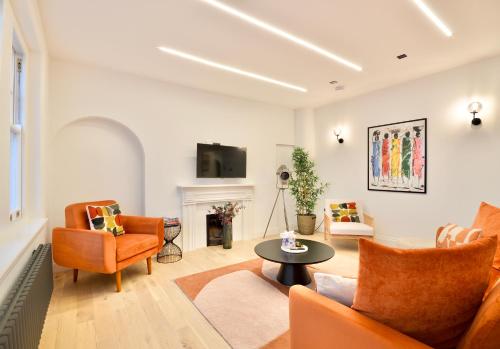 a living room with orange furniture and a fireplace at Newly Refurbished w/ River Views in London