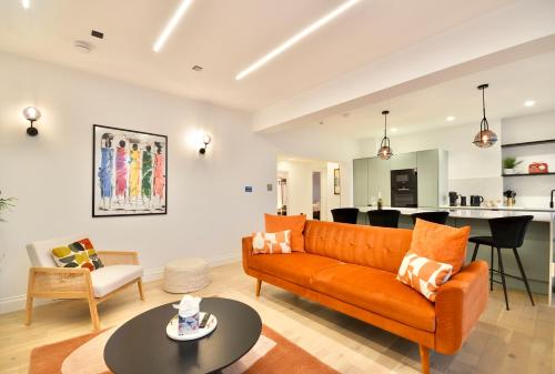 a living room with an orange couch and a table at Newly Refurbished w/ River Views in London