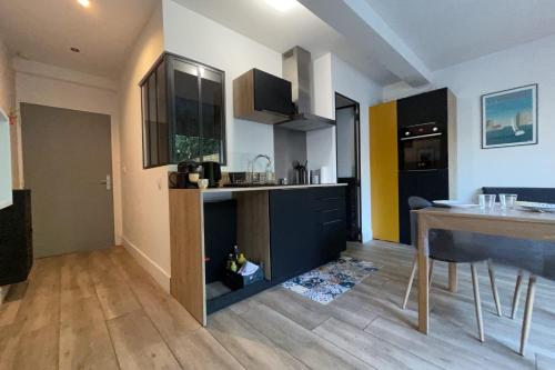 une cuisine avec des placards noirs et une table de cuisine dans l'établissement Cosy and refined 1-bedroom apartment with garden, à La Rochelle