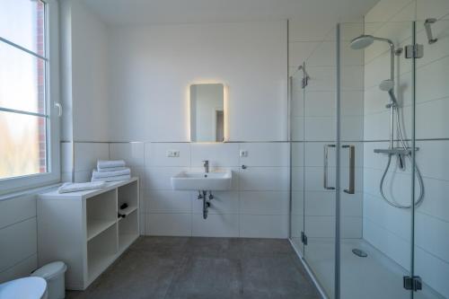a white bathroom with a sink and a shower at Aurora Schaar 2 in Wilhelmshaven