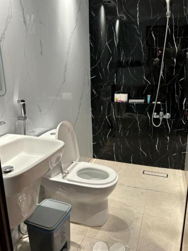 a bathroom with a white toilet and a black shower at ديباج للشقق المخدومة in Dammam