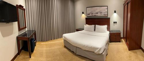 a hotel room with a bed and a television at ديباج للشقق المخدومة in Dammam