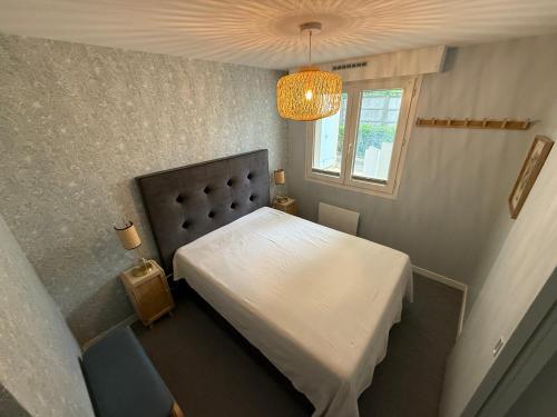 - une chambre avec un lit blanc et un lustre dans l'établissement Appartement 100m plage de Nauzan St Palais sur mer, à Saint-Palais-sur-Mer