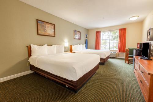 a hotel room with two beds and a television at Hotel Avenida, San Clemente Beach in San Clemente