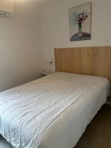 - un lit blanc dans une chambre avec un vase de fleurs dans l'établissement T2 le Côte d'Azur, au Lavandou