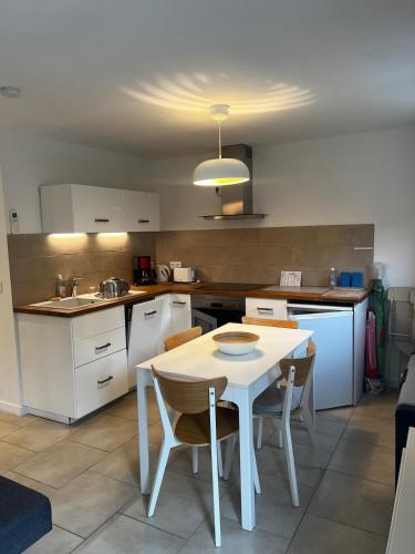 - une cuisine avec une table et des chaises blanches dans l'établissement T2 le Côte d'Azur, au Lavandou