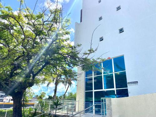 a tree in front of a white building at Flamboyant Oceania Flats in João Pessoa
