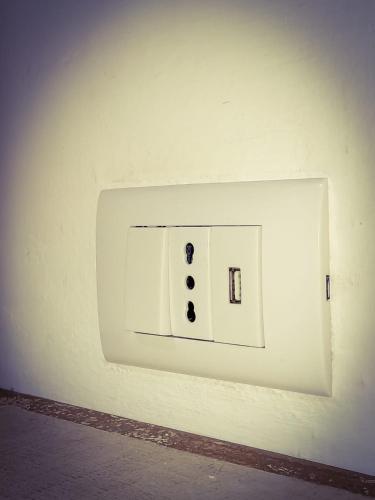 a white light switch on a wall at La Casina in Murlo