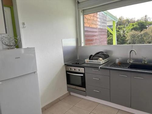 a kitchen with a sink and a stove and a window at Appartement confortable à Le Gosier avec piscine in Le Gosier