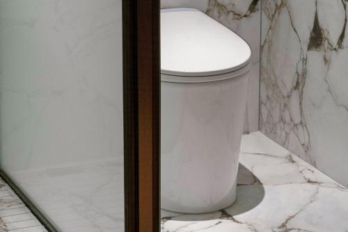 a white toilet in a bathroom with marble walls at Chengdu Dafang Hotel 大方酒店 in Chengdu