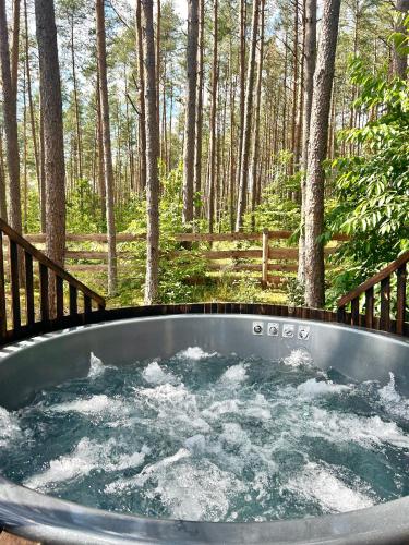 a tub with water in it in the woods at Domek lubiana180 SCANDI wśród drzew jacuzzi taras na dachu jezioro Kaszuby Pieski tylko do 10kg za dodatkową opłatą in Grzybowo