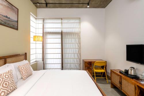 a bedroom with a bed and a desk and a television at Wandr Indiranagar, Bangalore in Bengaluru