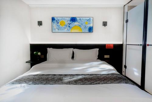 a bed in a bedroom with a painting on the wall at Chengdu Dafang Hotel 大方酒店 in Chengdu