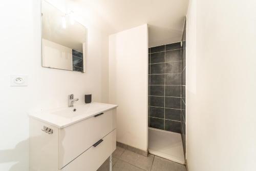 une salle de bain blanche avec un lavabo et un miroir dans l'établissement Le Cosmo - Cosy appart 2 pers-Brotteaux-Métro B, à Lyon