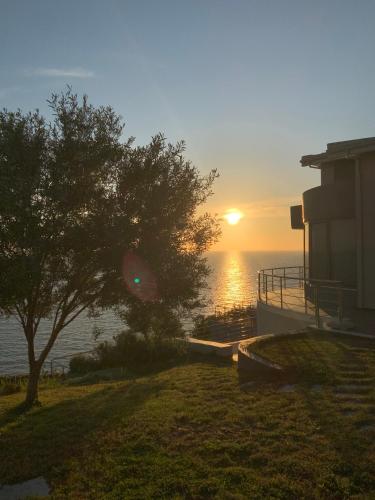 a sunset over the water with a house and a tree at Casa del Mar in Preveza