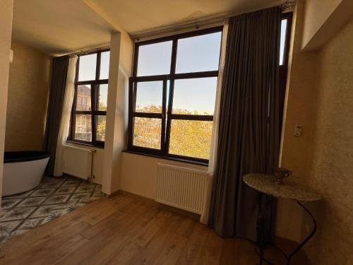 an empty room with two large windows and wooden floors at Wine Hills in Tbilisi City