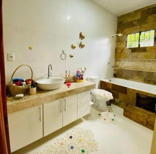 a bathroom with a sink and a tub and a toilet at Chácara Bela Vista in Benevides