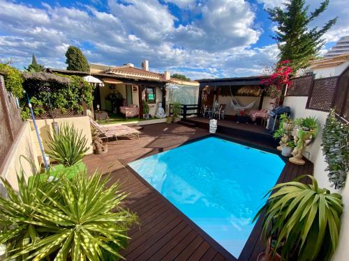 una piscina en un patio trasero con terraza de madera en Bungalow Aloha, Piscina Privada, Playa y Barbacoa, en Benalmádena