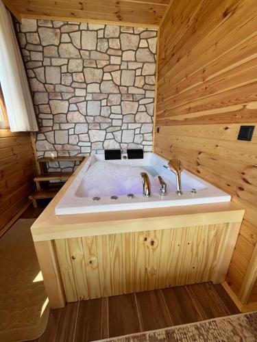 a bath tub with two faucets in a wooden bathroom at Ayder Defne Suit Ev in Çamlıhemşin