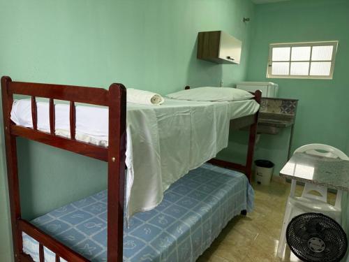 a bedroom with two bunk beds and a bench at Pousada Tortuga in Anchieta