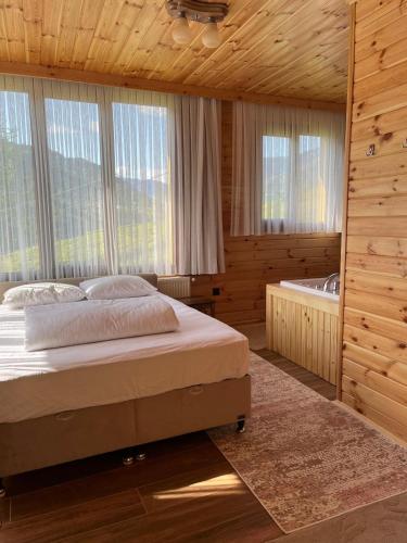 a bedroom with a bed and a tub and windows at Ayder Defne Suit Ev in Çamlıhemşin
