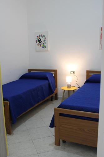 a bedroom with two beds and a table with a lamp at Vigata Sea in Porto Empedocle
