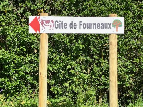 a sign on two wooden poles in front of a bush at Gîte de Fourneaux in Pont-d'Ouilly