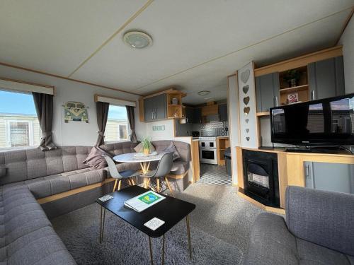 a living room with a couch and a tv at Meadow View 158 - Golden Palm, Pet friendly, WiFi, bed linen - Meadow Lakes Caravan & Lodge Hire in Skegness