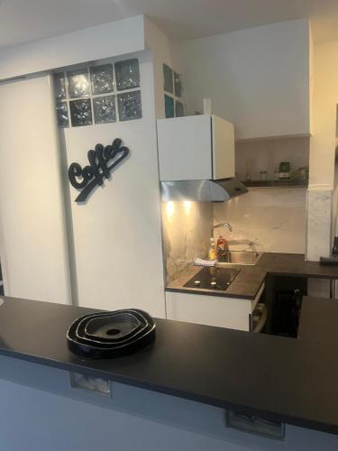 une cuisine avec un comptoir noir dans l'établissement QUEL appart, à Issy-les-Moulineaux