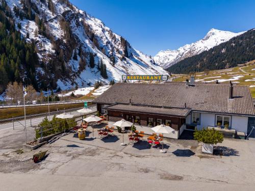 a building with tables and chairs in front of a mountain at Gasthaus Rheinwaldstube in Nufenen