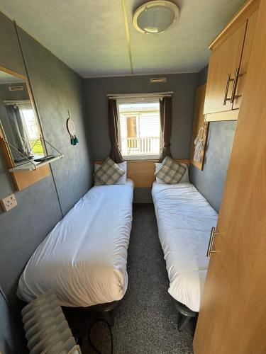 two beds in a small room with a window at Meadow View 158 - Golden Palm, Pet friendly, WiFi, bed linen - Meadow Lakes Caravan & Lodge Hire in Skegness