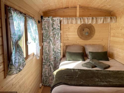 Ce lit se trouve dans une cabane en rondins dotée d'une fenêtre. dans l'établissement La Caminade, à Bourg-de-Bigorre